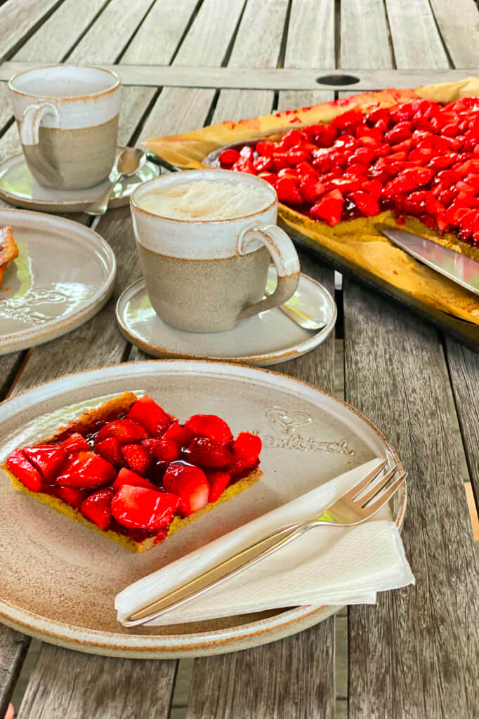 Erdbeerkuchen vom Blech mit Kaffeetassen.