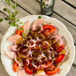 Saure Extrawurst mit Zwiebelringen, Tomaten und Kürbiskernöl